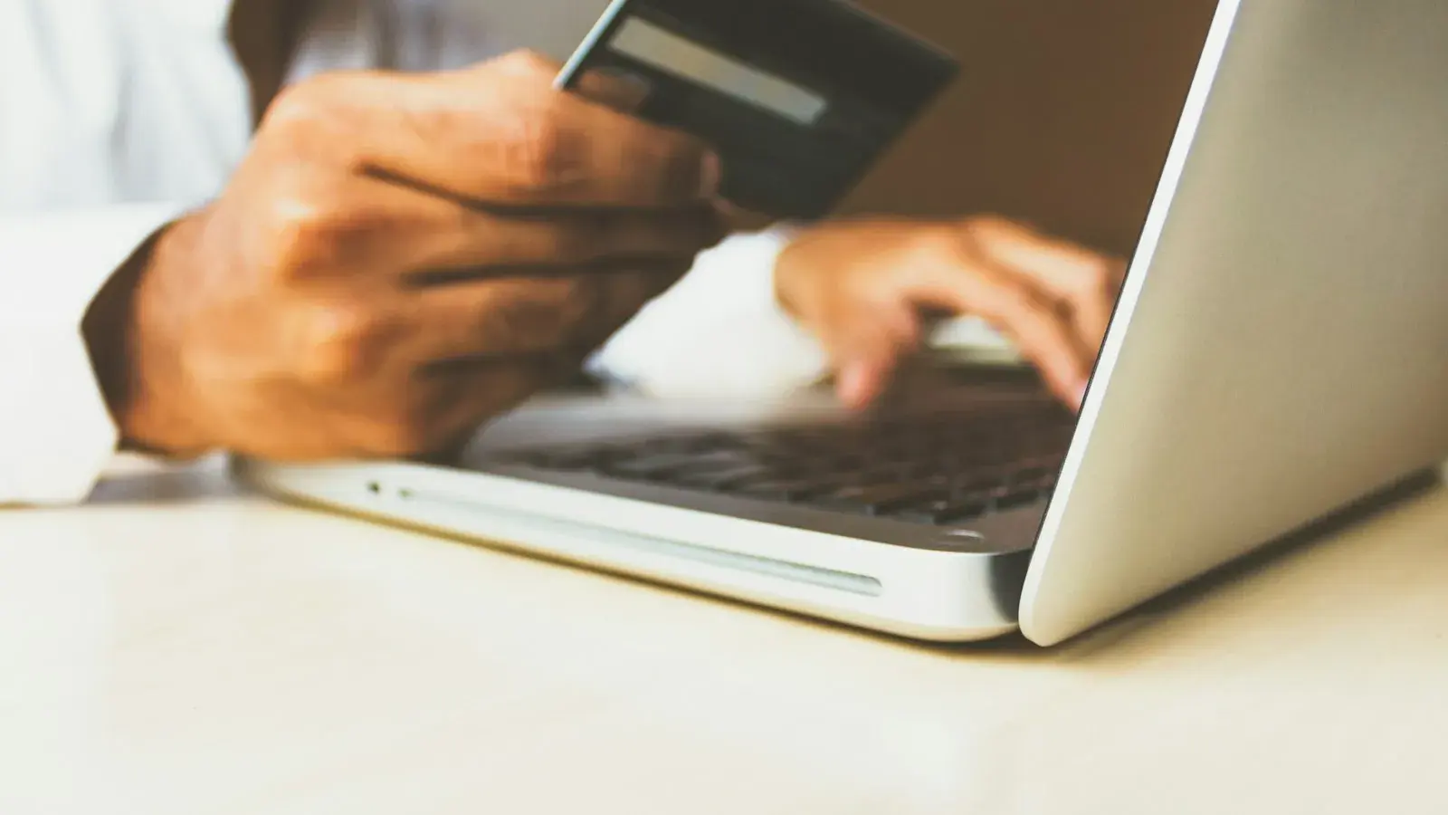Person using a laptop and holding a credit card, representing online payments and Stripe Atlas alternatives